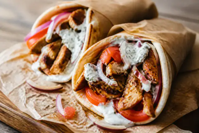 Pains pita garnis de poulet grillé, tomate, oignon rouge et sauce tzatziki