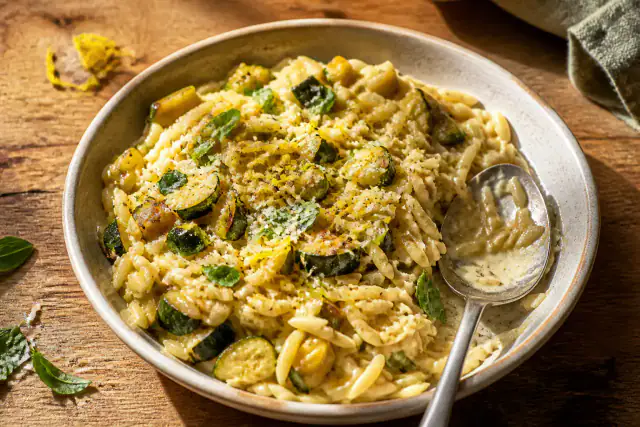 Orzo crémeux aux courgettes, Parmesan et zestes de citron dans une assiette creuse