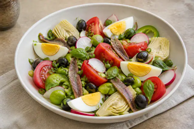 Salade niçoise traditionnelle avec tomates, œufs, anchois, poivron vert, radis et olives noires