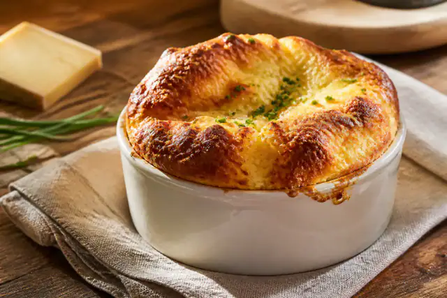 Soufflé au Comté haut et doré dans un plat en porcelaine avec ciboulette