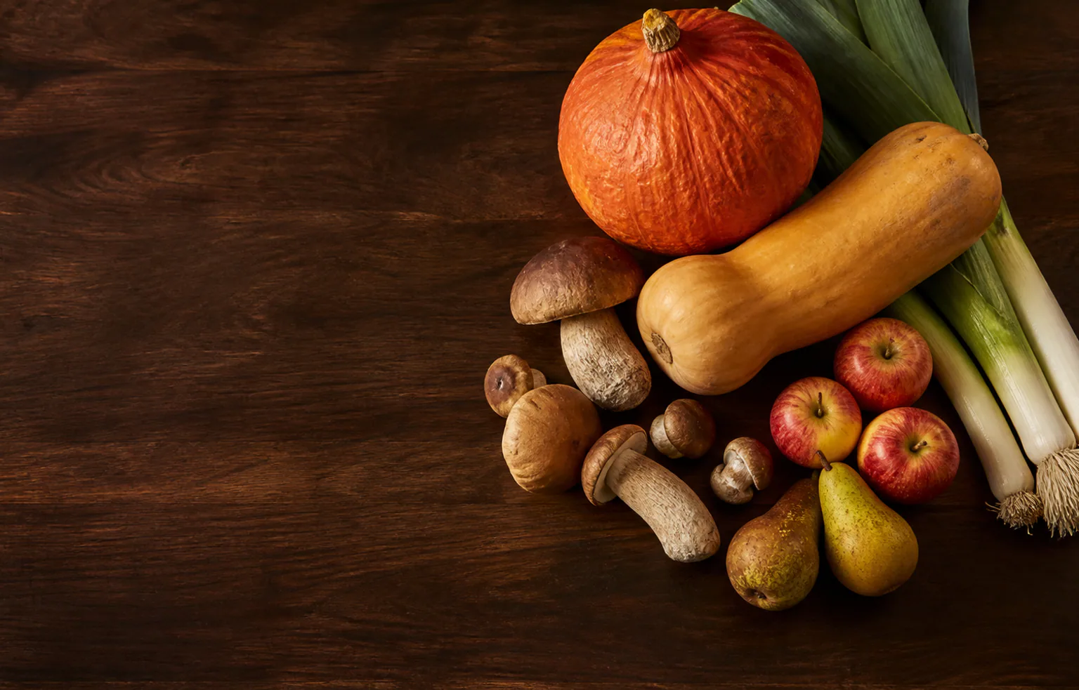 Potiron, champignons, poireaux et pommes posés sur un plan de travail de cuisine en automne