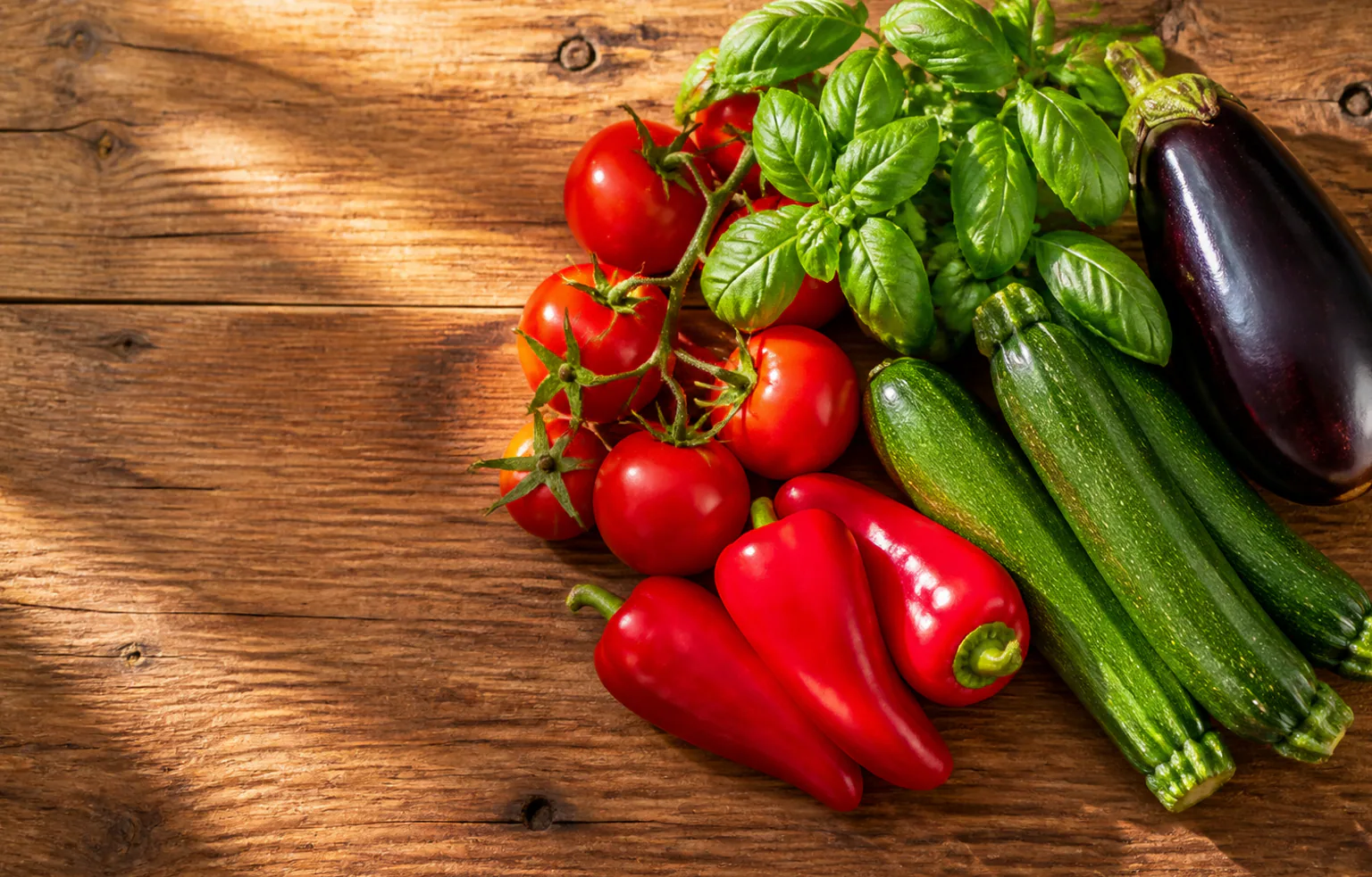 Tomates, courgettes, aubergines et basilic frais posés sur une table de cuisine en été
