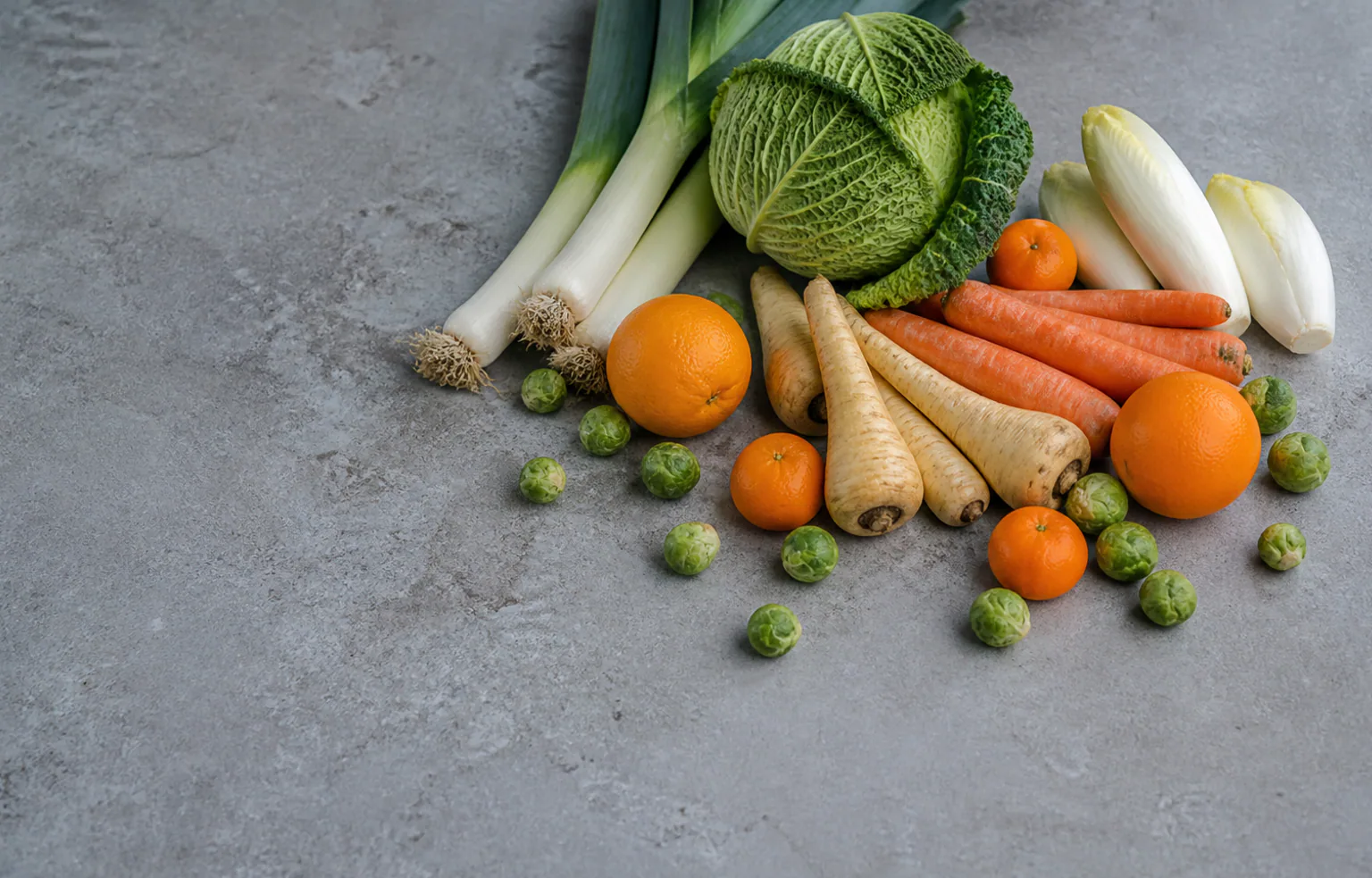 Poireaux, choux, endives et agrumes posés sur un plan de travail de cuisine en hiver